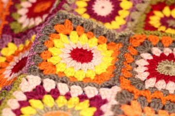 Granny square crocheted blanket with different colors motives, retro vintage craft handmade handiwork crocheting, beautiful plaid photo cozy winter or autumn background wool thing yarn warm bohemian