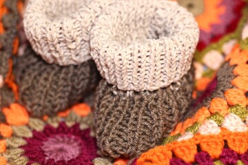 Baby knitted booties shoes handmade craft cute little things concept of childhood motherhood cozy home and crocheted colorful blanket beautiful photo