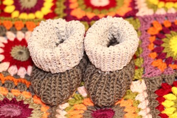 Baby knitted booties shoes handmade craft cute little things concept of childhood motherhood cozy home and crocheted colorful blanket beautiful photo