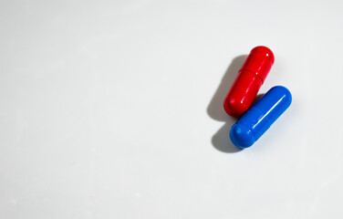 Red and Blue Pill Capsules on White Background with Strong Shadows © Anna Hoychuk