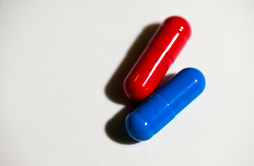 Red and Blue Pill Capsules on White Background with Strong Shadows © Anna Hoychuk