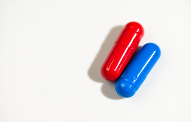 Red and Blue Pill Capsules on White Background with Strong Shadows © Anna Hoychuk
