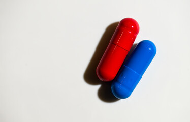 Red and Blue Pill Capsules on White Background with Strong Shadows © Anna Hoychuk
