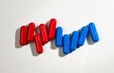 Red and Blue Pill Capsules on White Background with Strong Shadows © Anna Hoychuk