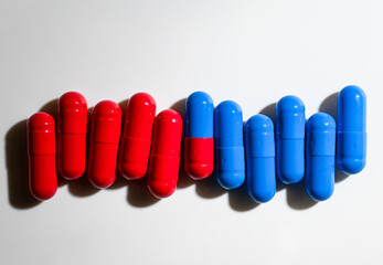Red and Blue Pill Capsules on White Background with Strong Shadows © Anna Hoychuk
