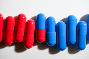 Red and Blue Pill Capsules on White Background with Strong Shadows © Anna Hoychuk