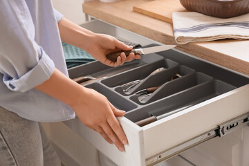 Woman taking knife from open drawer in kitchen