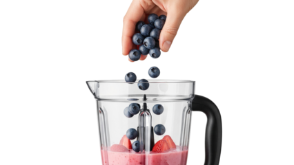 Hand adding fresh blueberries into a blender filled with strawberries and smoothie mix isolated on transparent background