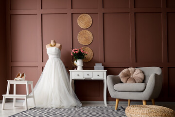 Interior of room with wedding dress, table and armchair