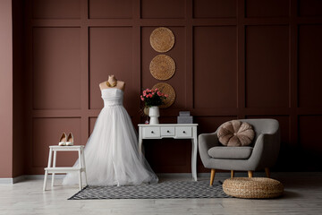 Interior of room with wedding dress, table and armchair
