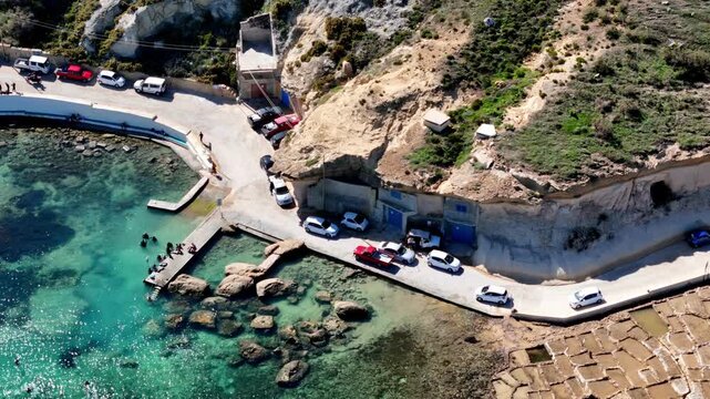 historic fishing village of Xlendi Gozo Malta during a bright sunny summer morning featuring deep blue Mediterranean waters emerald green valley slopes and white limestone architecture