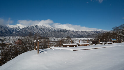 高台から望む街並みと冬の北アルプス