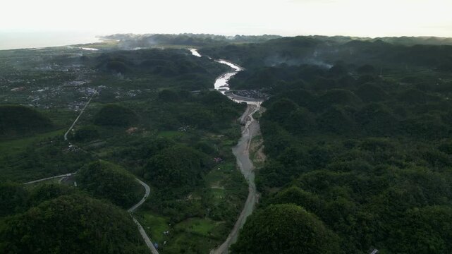 Picturesque aerial flyover of verdant, tropical valley with winding Pajo river amid rolling hills - Virac, Catanduanes, Philippines