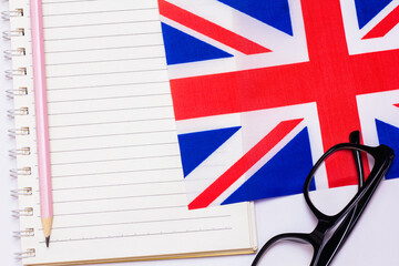The concept of learning English includes the British flag and a notebook on a white background.
