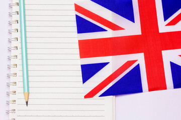 The concept of learning English includes the British flag and a notebook on a white background.