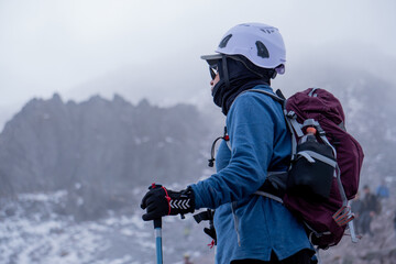 Hiker wearing helmet and backpack trekking a snowy mountain landscape