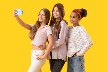 Teenage girls taking selfie on yellow background
