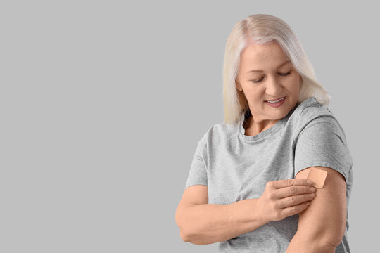 Mature woman applying contraceptive patch on light background. Menopause concept