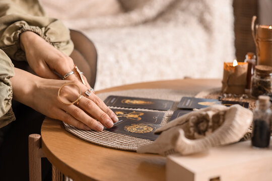 Female fortune teller reading tarot cards at table in room