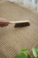 Cleaning a carpet with a broom in a living room space