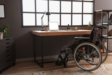 Interior of dark office with workplace and wheelchair