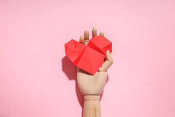 Wooden craft with a red origami heart on pink