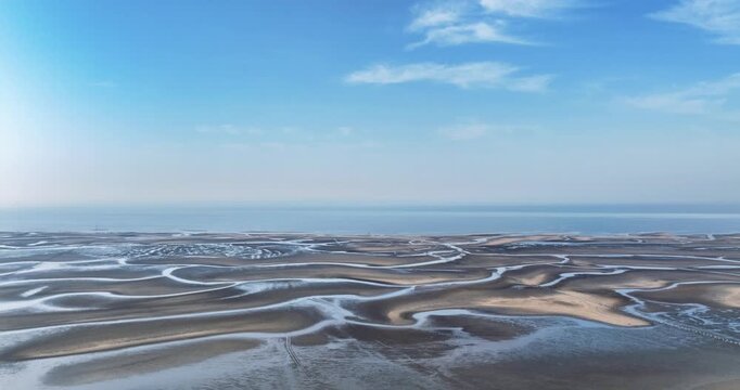 Aerial time-lapse of morning light revealing intricate tidal flat textures on the Yellow Sea coast near Rizhao, Shandong Province, China