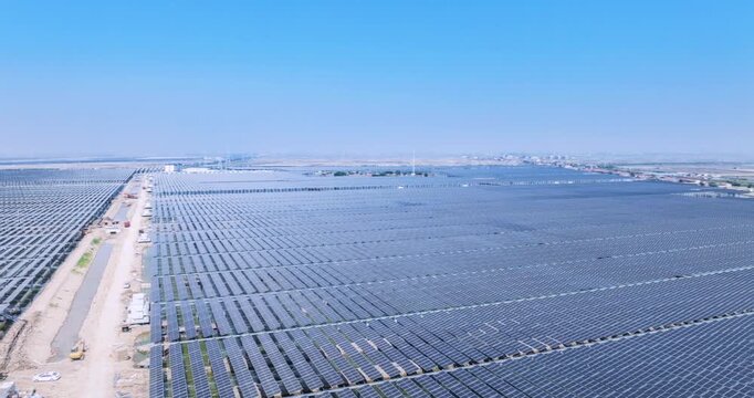 Aerial time-lapse of a large-scale solar photovoltaic farm under construction in a coastal area, renewable energy development and sustainable infrastructure.