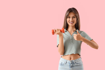 Young woman with dumbbell showing thumb-up on pink background. Immunity concept
