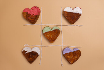 Tic tac toe food game Valentine's Day Birthday holiday present gift idea Delightful and vibrant heartshaped pastry croissant treat, beautifully topped with colorful frosting galore. Copy space. Food