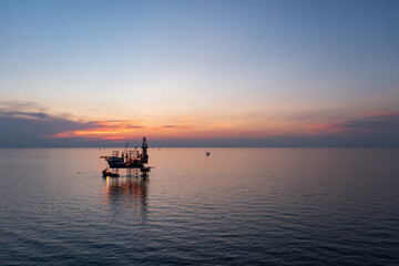 Aerial view of offshore jack up rig in a shipyard during sunset for oil and gas exploration and production.