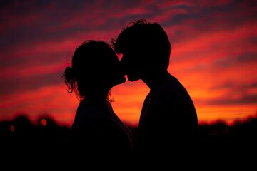 Romantic silhouette of two figures kissing against a vibrant, colorful sunset background