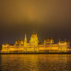 Fototapeta premium The Hungarian Parliament Building at night with lights and illumination, panorama view over the Danube river on a chilling winter day