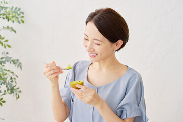 リビングでキウイフルーツを食べる女性