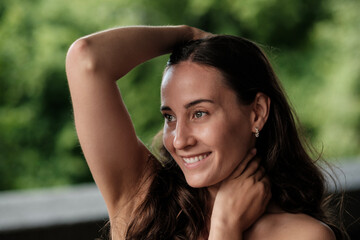Fototapeta premium Beautiful smiling woman holding her hair and touching her neck