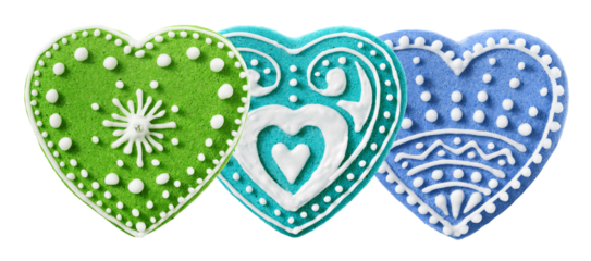 three heart-shaped cookies decorated with colorful icing in green, turquoise, and blue, adorned with intricate white patterns and dots.