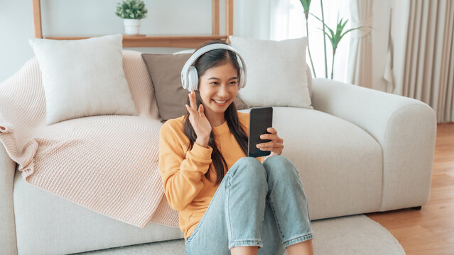 Asian woman listening to music with headphones and mobile phone in living room at home. Headset and sound with song, radio, podcast for motivation and smile