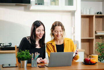 Two women working from home using laptop and phone. Teamwork, collaboration, freelance lifestyle, online business, remote work