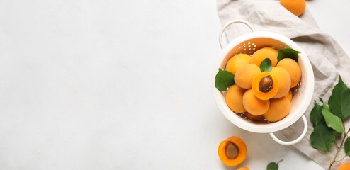 Colander full of ripe apricots on light background with space for text