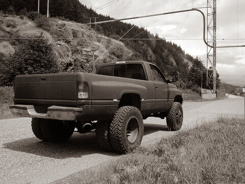 1996 Dodge Ram 3500 dually with large tires parked in a forested area near a mountain black and white