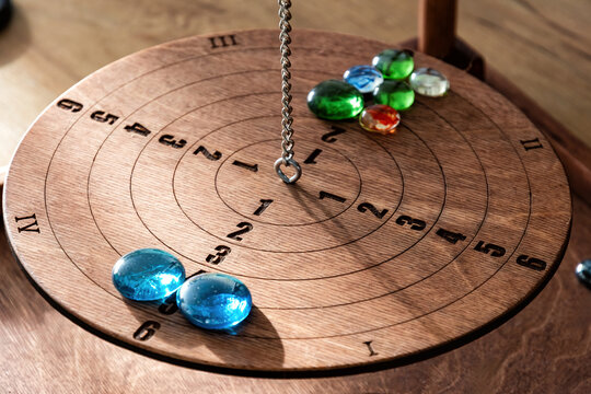 Close-up of a vintage wooden balance board game. Colorful glass marbles, engraved numbers, and a chain symbolize strategy, decisions, and precision - Powered by Adobe