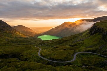 Winding road through green valley at sunset