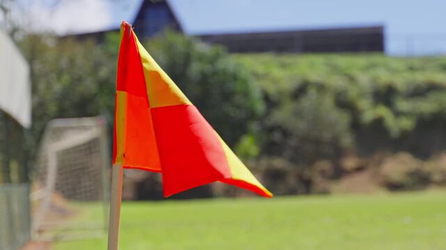 Soccer corner flag waving in the wind on a sports field under bright sunlight.