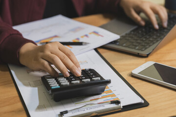 Accountant working Financial investment on calculator and laptop with tablet on withe desk.