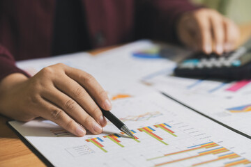 Accountant working Financial investment on calculator and laptop with tablet on withe desk.