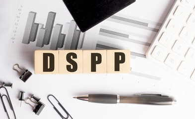 DSPP acronym on wooden blocks with financial documents, pen, calculator and office tools on white desk