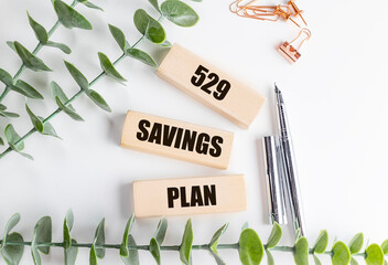 529 savings plan phrase on wooden blocks with pens, clips and green leaves on white background