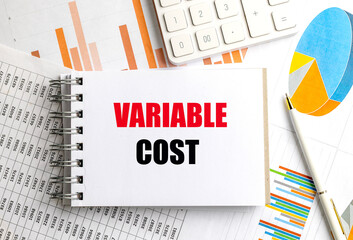 Variable cost phrase on notepad surrounded by financial documents, pen and calculator
