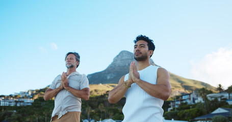 Men, prayer and meditation for mindfulness, beach and routine for peace, low angle and stress relief. Outdoor, space and people with spiritual awareness in nature, namaste and faith for wellness