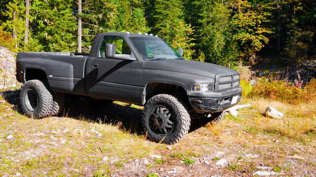 Black second generation Dodge Ram 3500 dually with black matte paint and big tires parked in the forest on a sunny day